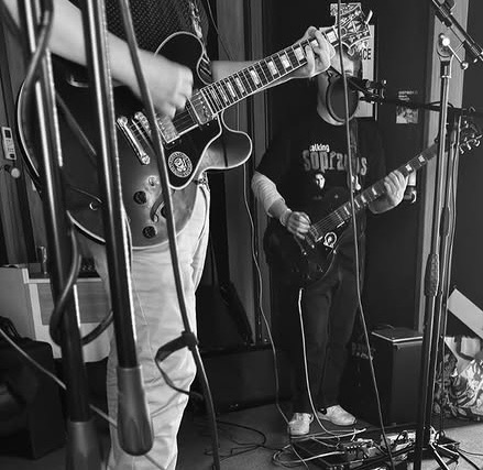 Guitarists recording in a studio with microphones set up